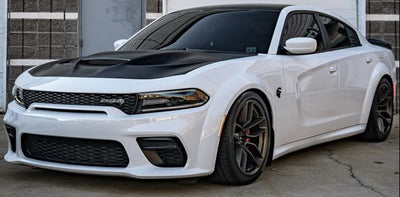 White Dodge Charger SRT Widebody with black hood and red brake calipers parked on a concrete surface.