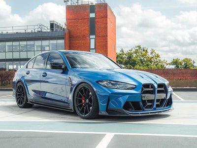 Blue BMW M3 competition car parked on a street with a building in the background