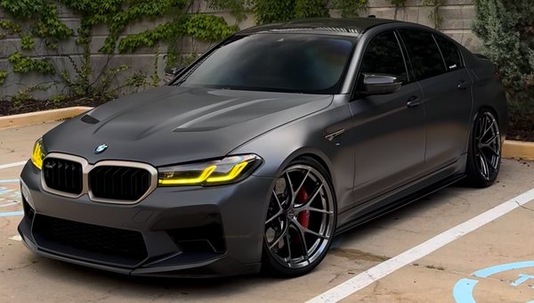 Gray BMW car parked on a street with a building and trees in the background