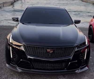Black Cadillac car parked on a dock with a city skyline in the background - CT5-V Blackwing